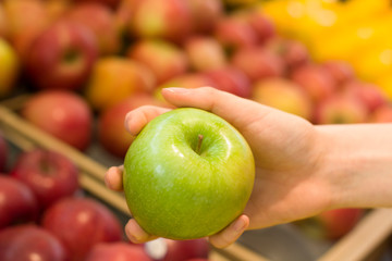 Female hand choosing apple in the store. Concept of healthy food, bio, vegetarian, diet.