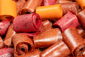 Closeup view photography of tasty healthy homemade organic dessert made of different kinds of fruits. Rolls of dried fruit leather perfect for eating as healthy snack.