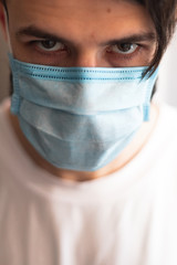 a young man wearing a mask is quarantined at home