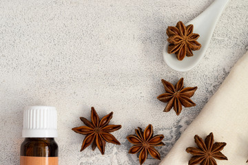 Essential anise oil  in glass bottle and natural anise star spice on a white concrete background. Aromatherapy and Ayurveda concept.