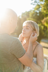 man gives woman to listen music on headphones. couple in love on the street