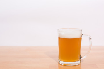 Man holding beer mug full of beer on wooden table on white background