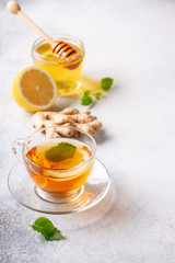 Cup of hot tea with ginger, lemon,mint and honey on concrete background.