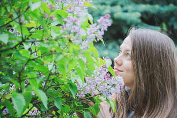 Fototapeta premium Young Girl Posing Near Lilac Bushes
