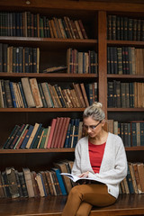 Young woman in library reading book