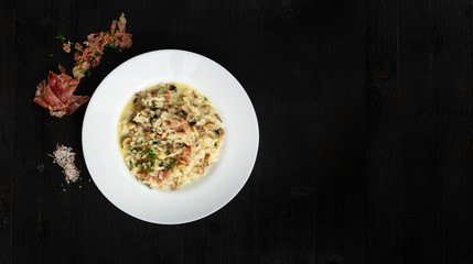 Super clean tatsy risotto with bacon and mushrooms. Round plate and wooden background with space for text. Good as banner or cover.
