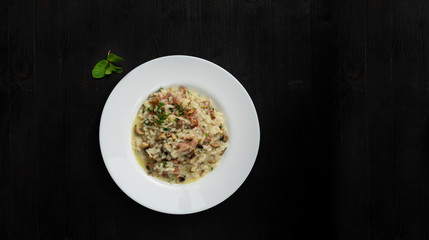 Super clean tatsy risotto with bacon and mushrooms. Round plate and wooden background with space for text. Good as banner or cover.