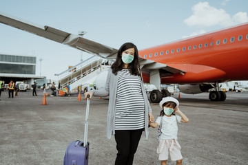 Pregnant mother and her daughter wear masks in the airport