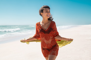 Carefree woman running and holding scarf at beach