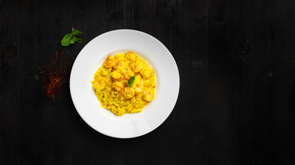 Super clean tatsy risotto with seafood and curry. Round plate and wooden background with space for text. Good as banner or cover.
