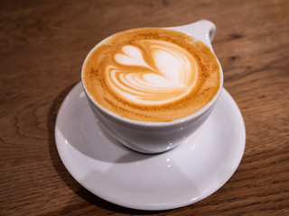 A coffee with a beautiful latte art heart on top