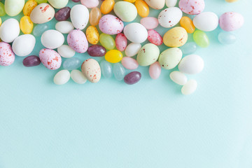 Happy Easter concept. Preparation for holiday. Easter candy chocolate eggs and jellybean sweets isolated on trendy pastel blue background. Simple minimalism flat lay top view copy space.