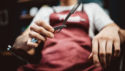 Sharp razor blade in hands of professional barber
