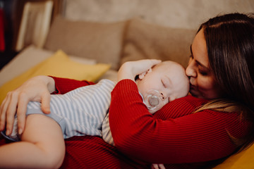 The baby sleeps on the mother's chest and stomach. Mom kisses and hugs the child.