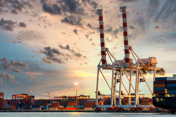 Background for cranes and industrial cargo ships in port at twilight.