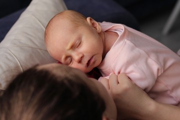 Beautiful mother and her little baby girl are hugging each other and looking through the camera