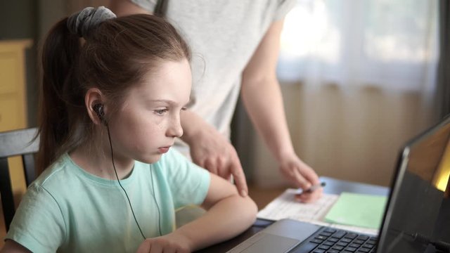 Online learning, distance education, mother helps little girl with homework on computer.