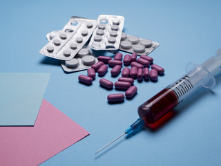 Multicolor pills and tablets and medical syringes with fluid on blue background. Macro. Top view. Medical concept. vitamins pills . copy space for test