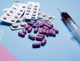 Multicolor pills and tablets and medical syringes with fluid on blue background. Macro. Top view. Medical concept. vitamins pills . copy space for test