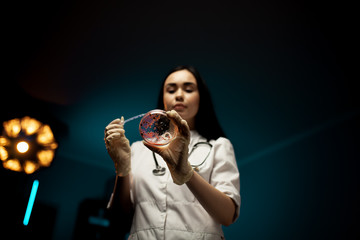 Professional biology scientist young woman wear white glove holding pipette with drop of red liquid...