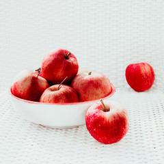 Red apples over a white chair in natural light