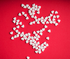 Small white love pills with a plastic bottle on red colorful table. Concept of love pills, potency, loneliness, heart disease. heart pills on red background