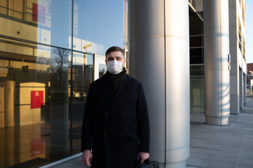 Handsome young caucasian man near his office wearing surgical face mask to protect from coronavirus covid-19 covid 19 virus