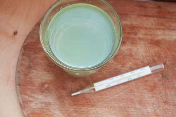 A glass of eucalyptus alcohol gargle and a thermometer. We treat a sore throat. Lower the temperature.