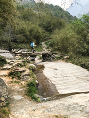 Hiker crossing a river on the Annapurna Circuit, in the Himalayas