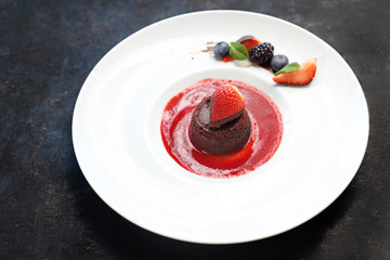 Chocolate cake with a liquid agent served with raspberry sauce.