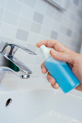 man disinfecting the faucet of a sink