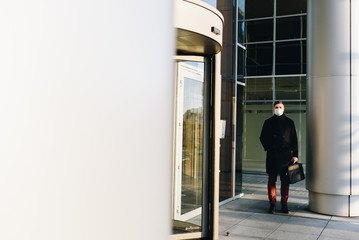 Caucasian young man near his office during coronavirus covid-19 virus epidemic wearing surgical face mask
