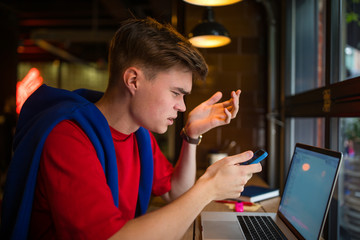 Frustrated angry man received on mobile phone e-mail with bad news, sitting in coffee shop with netbook.