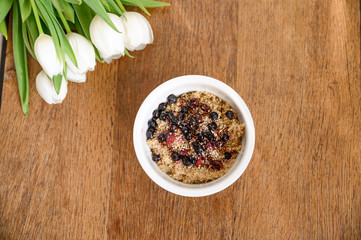 Fresh spring oatmeal, quinoa, healthy breakfast on wooden table.