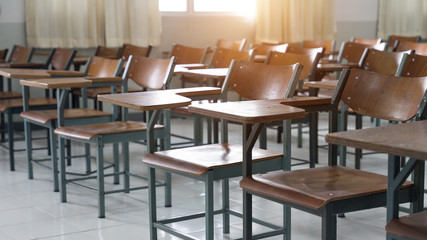 Empty classroom with a lot of chair with no student. Empty classroom with vintage tone wooden chairs. Back to school concept.