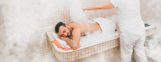 Turkish man receiving foam massage at hammam , spa weekend. Traditional oriental baths