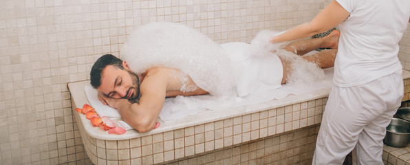 Turkish man enjoying foam massage in a Turkish bath. Hammam worker washes men's skin. Foam massage