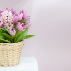 Beautiful bouquet of artificial tulips and hyacinth in a wicker basket.