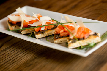 Bruschetta with olive and garlic pesto, with cherry tomato and parmesan leaves