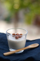 Glass of vanilla pudding with hazelnut topping and wooden spoon. Selective focus.