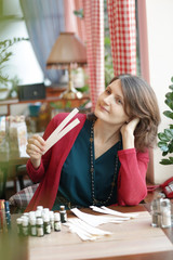 young woman in cafe with tea set smells perfumes with blotter close up photo