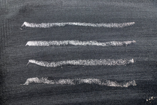 White color chalk hand drawing in set of wavy line shape on black board background