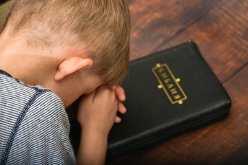 The boy reads the Bible and prays, worshiping the child in spirit and truth.