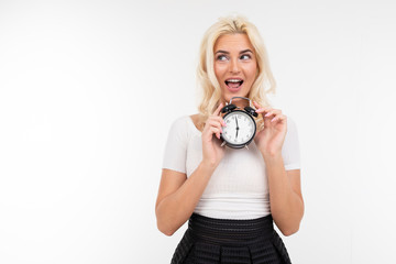 sexy woman in a white t-shirt holds an alarm clock on a white background with copy space