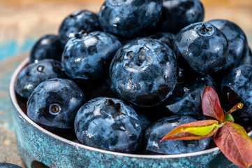 Fresh ripe blueberries in bowl on wooden background