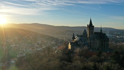 Schloss Wernigerode beim Sonnenuntergang, Drohnenfoto mit Sonne und dem Brocken im Hintergrund