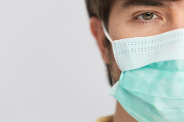 man wearing protection sterile mask looking to camera with one eye while covid-19