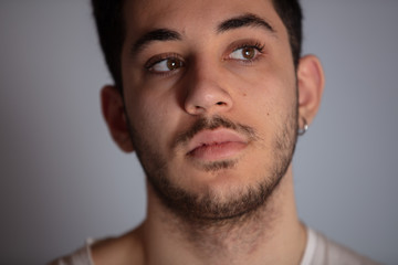 Obraz premium Close-up portrait of thinking handsome bearded man in white shirt isolated on grey background