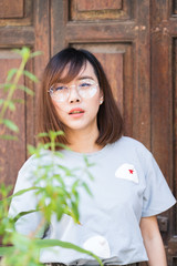 Portrait of fashion woman posing while wearing glasses against wooden door