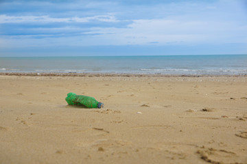 Fototapeta na wymiar Waste plastic bottle on sand. Garbage on the beach